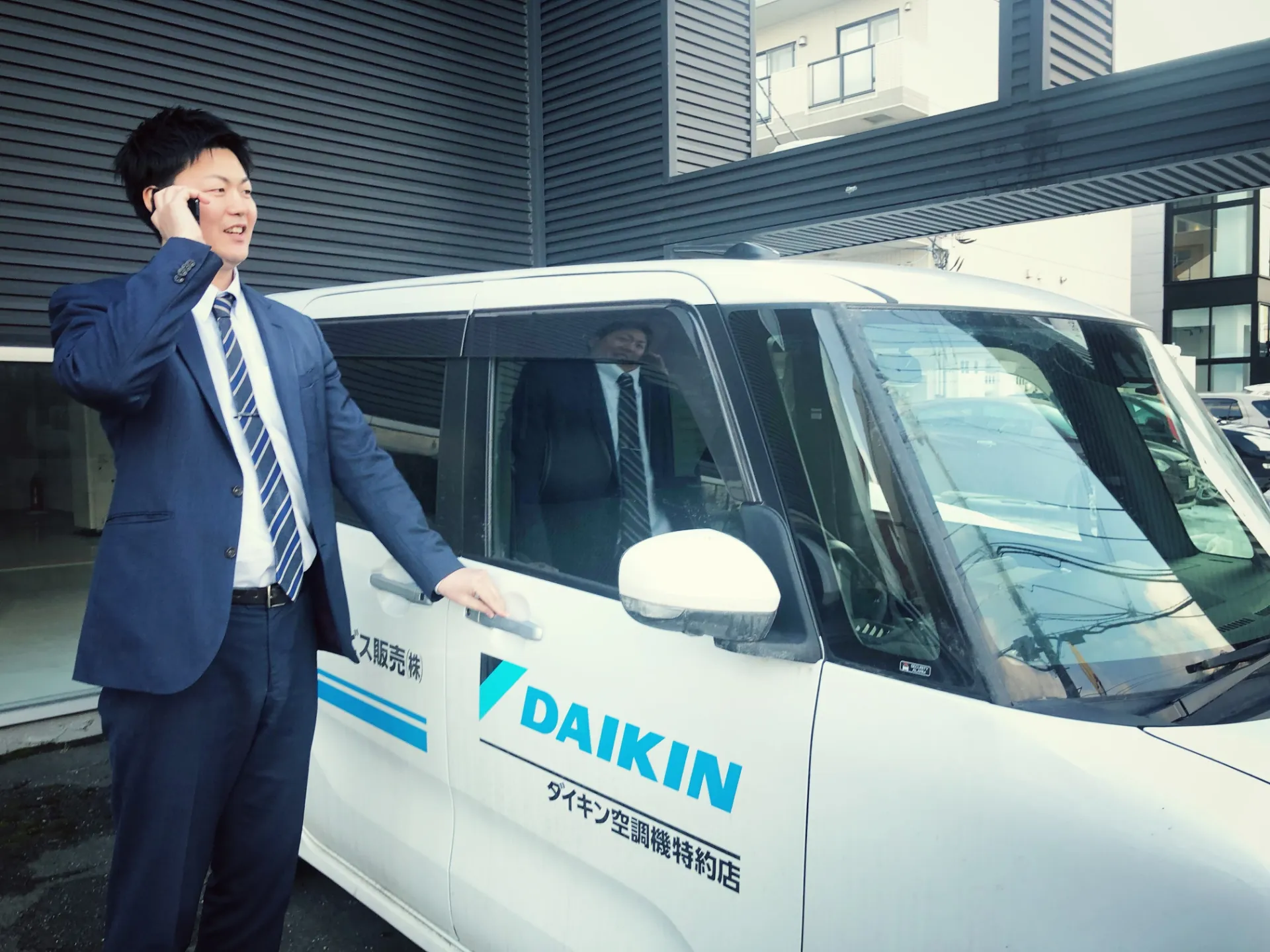 社用車の前に立つ営業担当者
