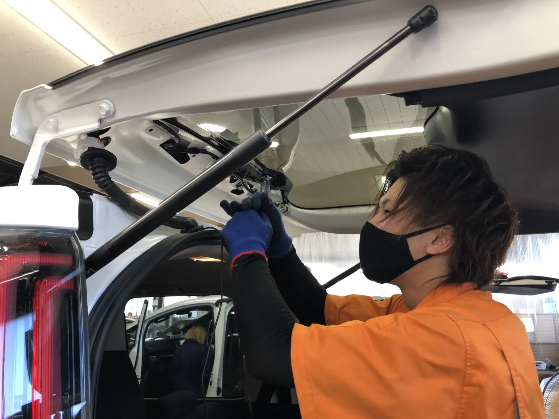 車のバックドアを開けて部品を取り付けるスタッフ